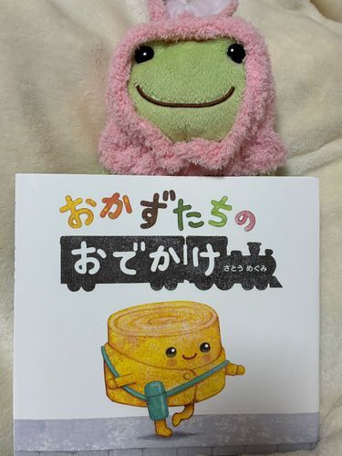 かわいいたまご焼きさんが駅のホームで機関車を待っていると、チキンライスちゃんがやってきて……その後にもチーズハンバーグくん、アスパラベーコンくんと美味しそうなおかずさんたちがやってくるケロ。その間に優しさのリレーが繋がれて行って、思わずにっこりしてしまったケロ。
ピーの明日のお昼ご飯は、お子様ランチが良いケロねえ〜！

おかずたちのおでかけ
作、絵・さとうめぐみ