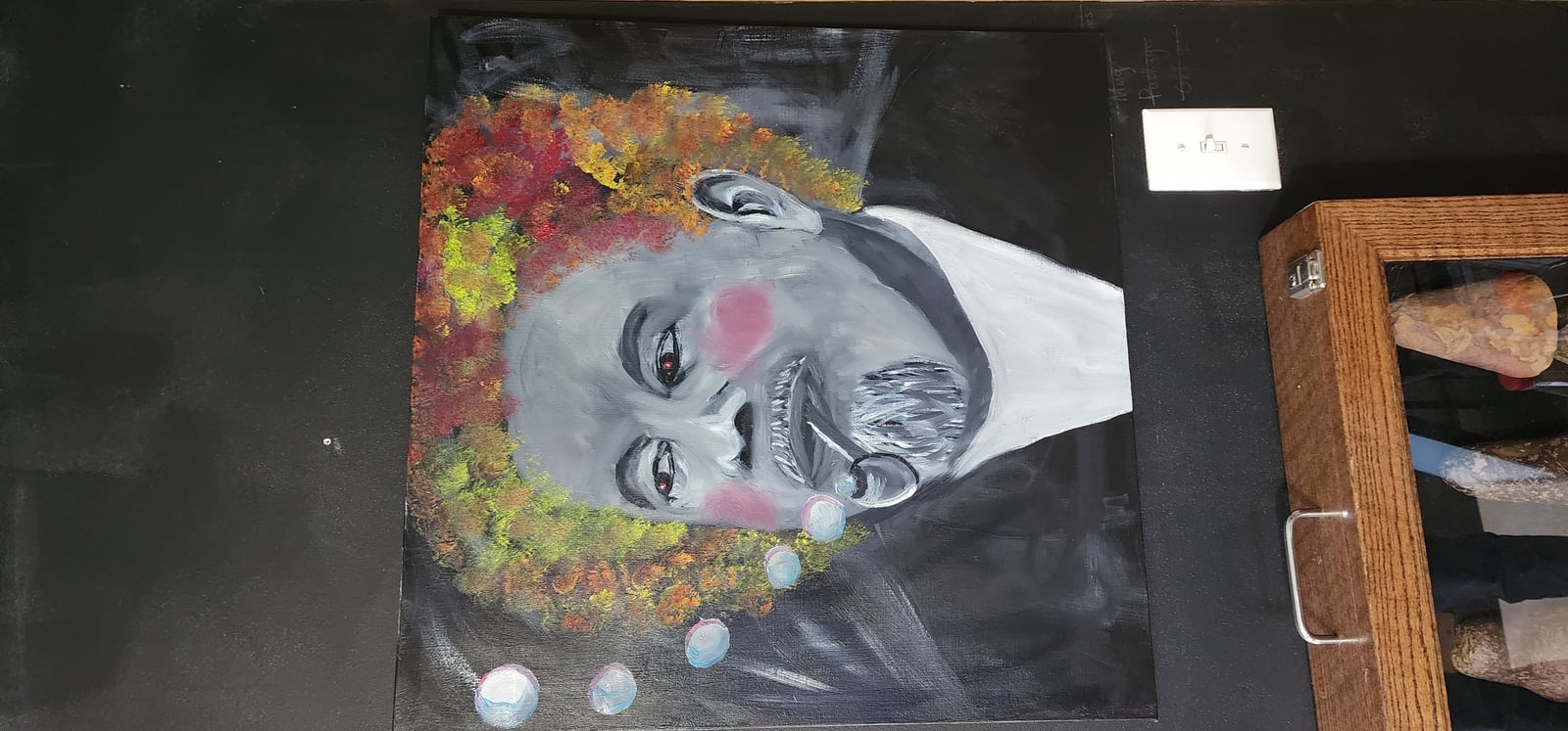 Berl Ives in a clown wig blowing bubbles.  