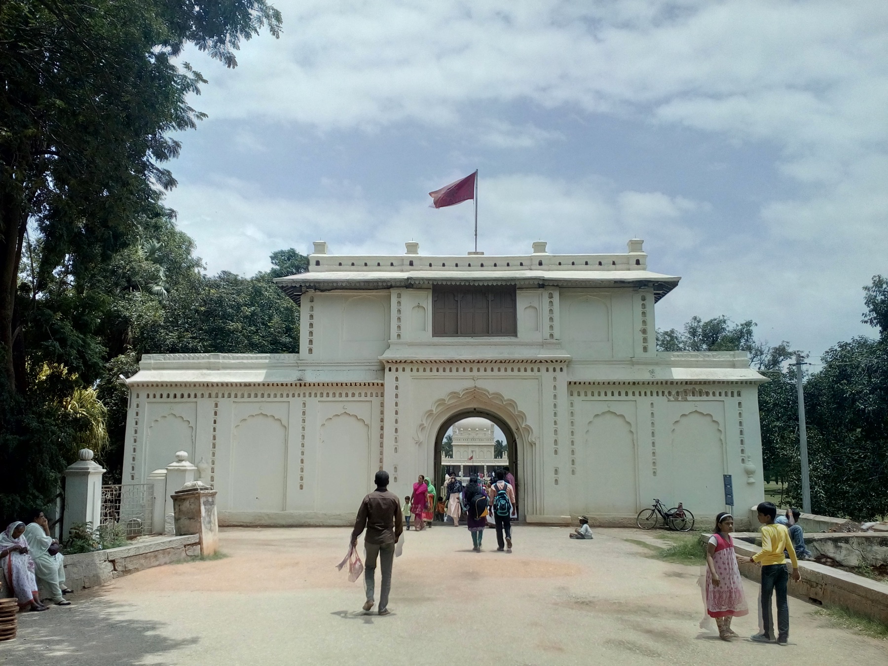 A white historic gateway opening onto the Srirangapatna road