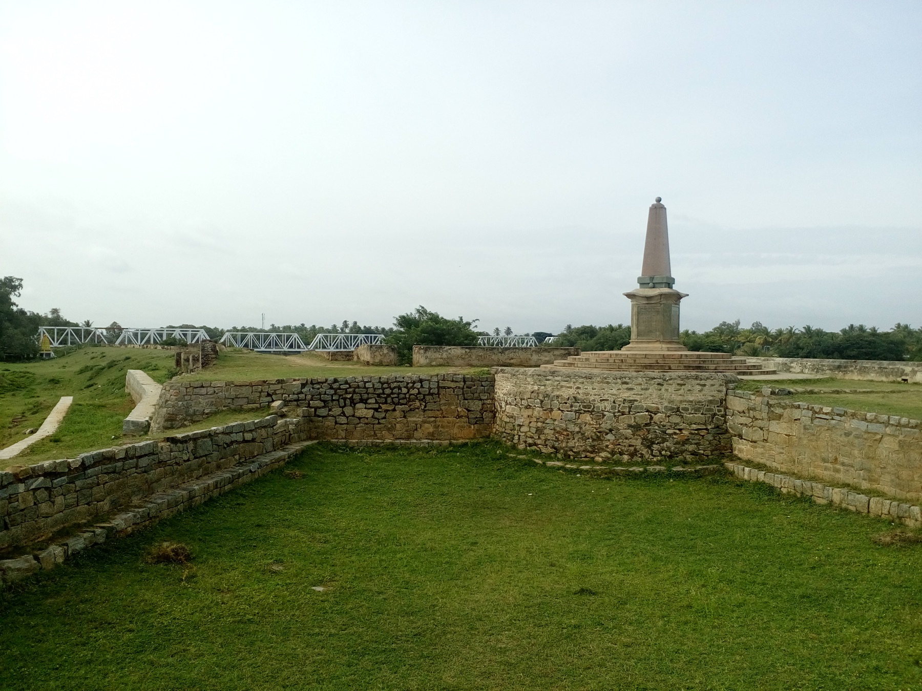 Fort earthworks and a memorial across the green Cauvery island