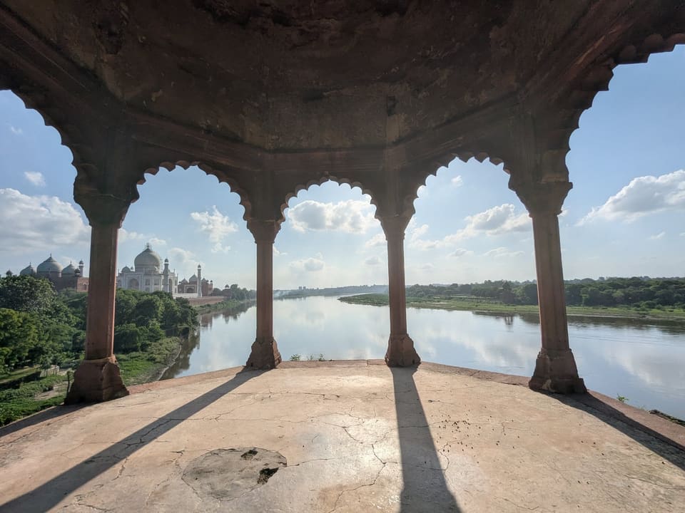 The Taj Mahal seen across a green river landscape from the Taj Nature Walk