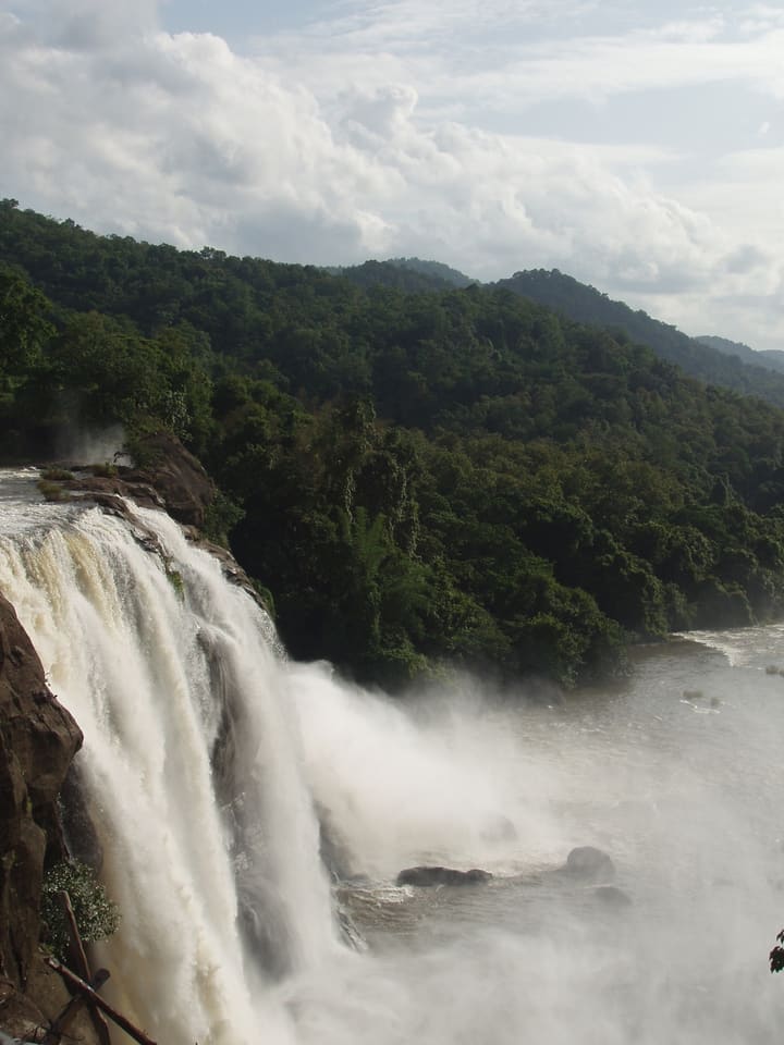 Athirappilly waterfall flowing through a broad forested river landscape