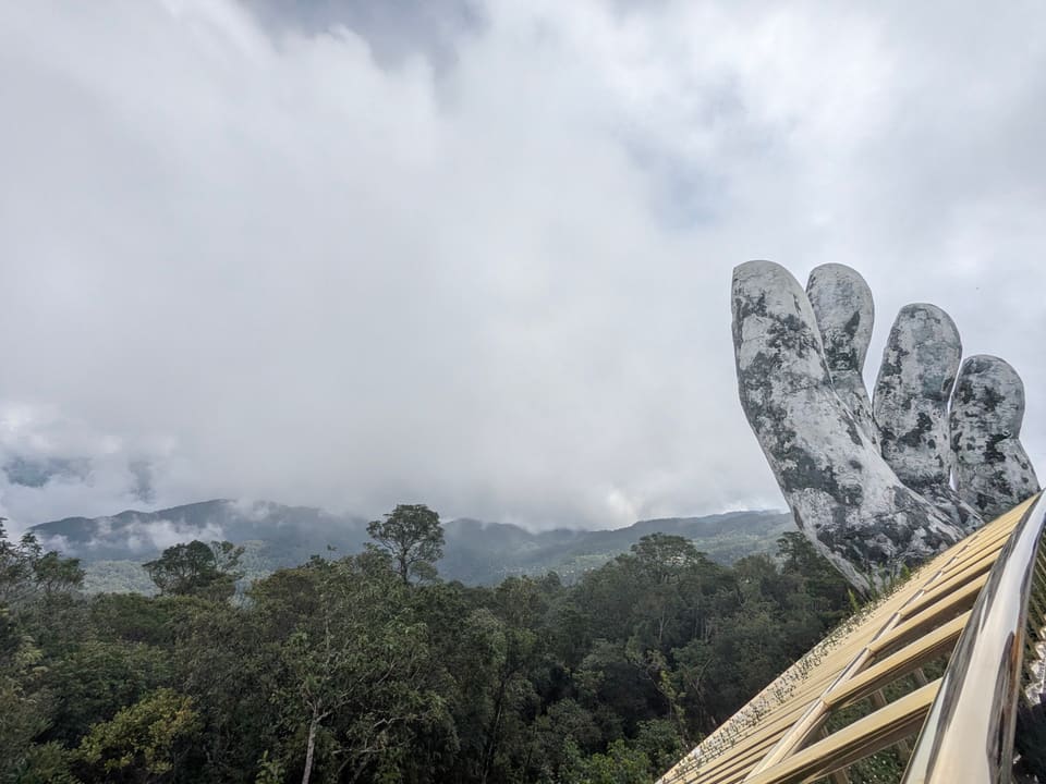 Giant stone hands of the Golden Bridge appearing through mountain mist