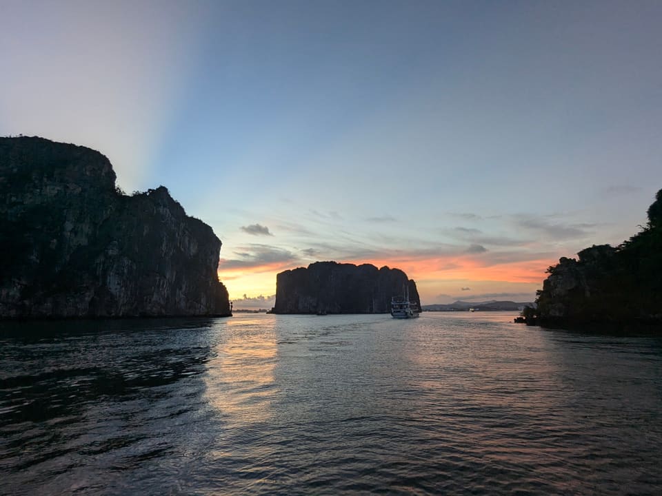 Last orange light between dark limestone islands in Ha Long Bay