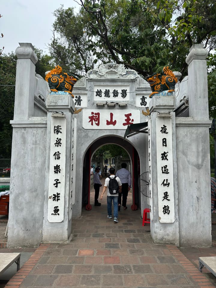 Stone gateway decorated with colourful creatures at Ngoc Son Temple