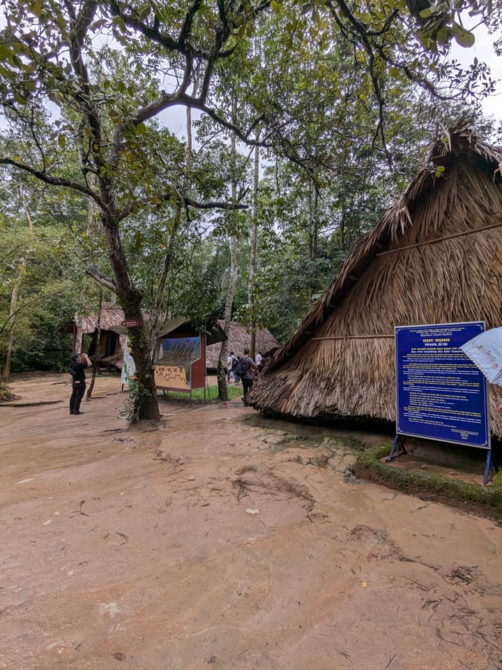 Palm-roofed structures among dense trees at the Cu Chi tunnels