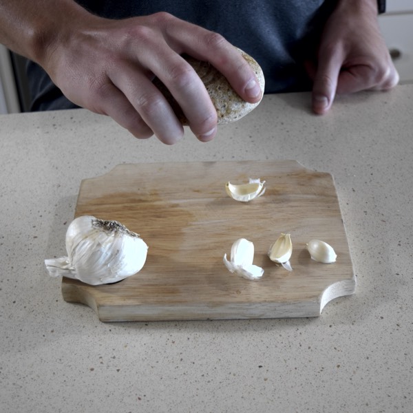 Holding a rock firmly in palm of hand to smash down onto garlic clove