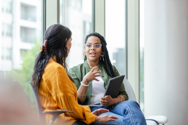 Female therapist engaging in a supportive conversation with a client during a counseling session in a modern, well-lit office, emphasizing mental health and emotional well-being.