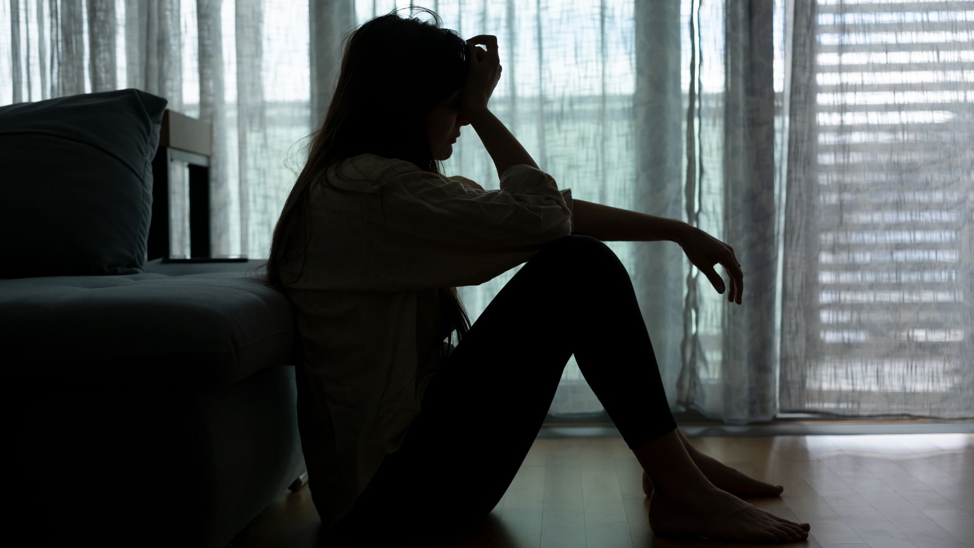 Women looking sad and overwhelmed in an empty room, showing signs of depression