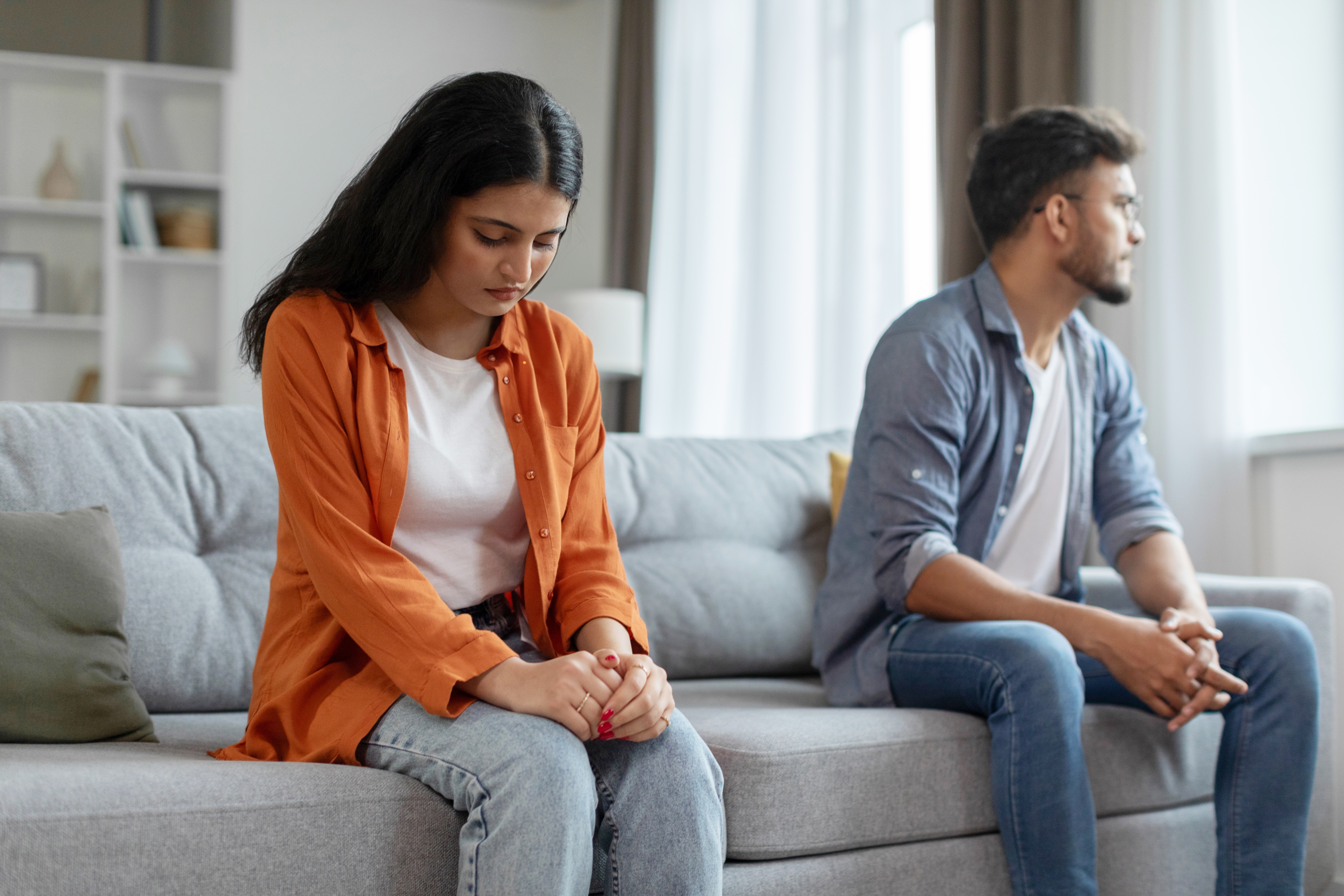 Indian couple sitting apart looking sad and distant, representing different stages of depression affecting relationships and mental health