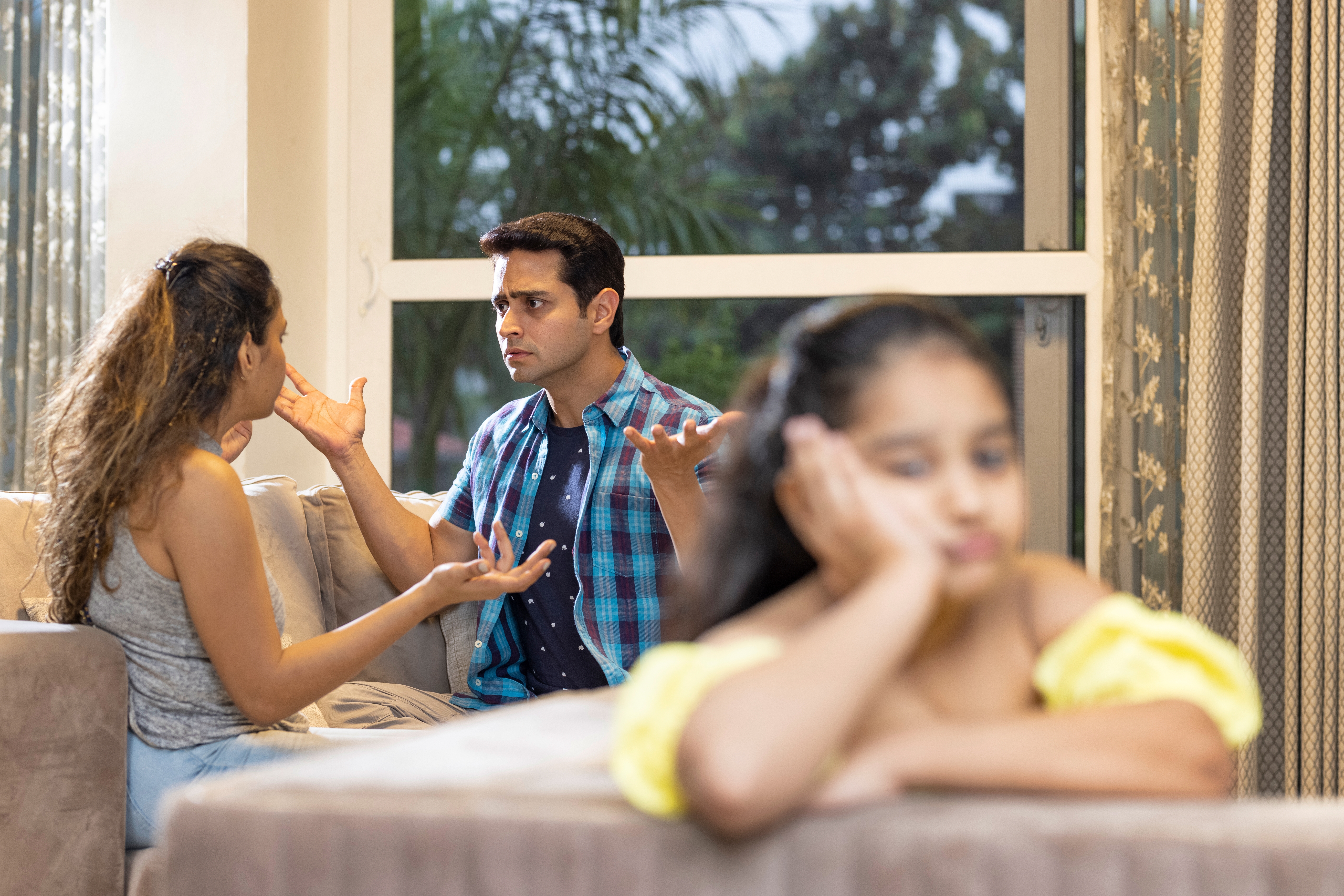Distressed child covering ears while parents argue in background, illustrating childhood trauma from domestic conflict and family dysfunction