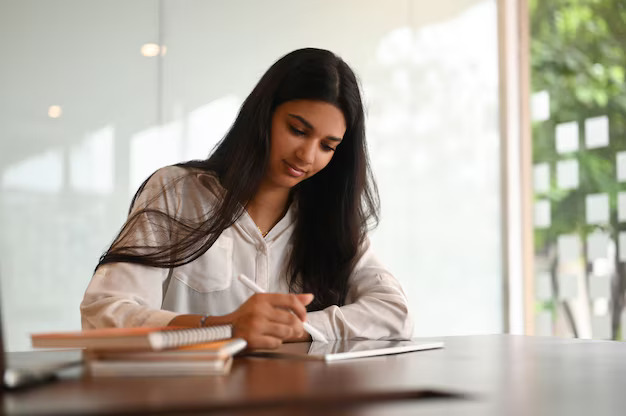 Businesswoman writing in a journal at her desk, reflecting and planning her schedule – representing mental health journaling and mood tracking for emotional balance.