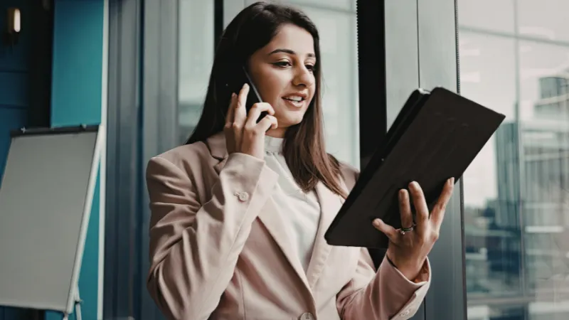 Empresaria hablando por teléfono mientras revisa su tablet — pidiendo presupuesto