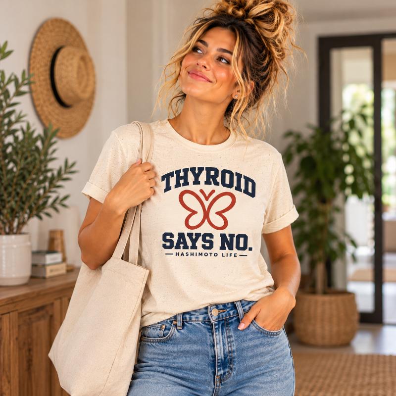 Frau im weißen Hashimoto T-Shirt mit dem Aufdruck Thyroid Says No und Schmetterlingsgrafik.