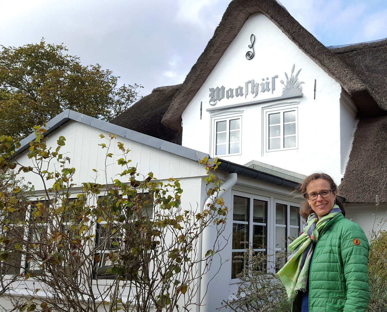 Gastgeberin Jeannette Springorum vor dem Reetdach-Ferienhaus Waashüs in Nebel auf Amrum