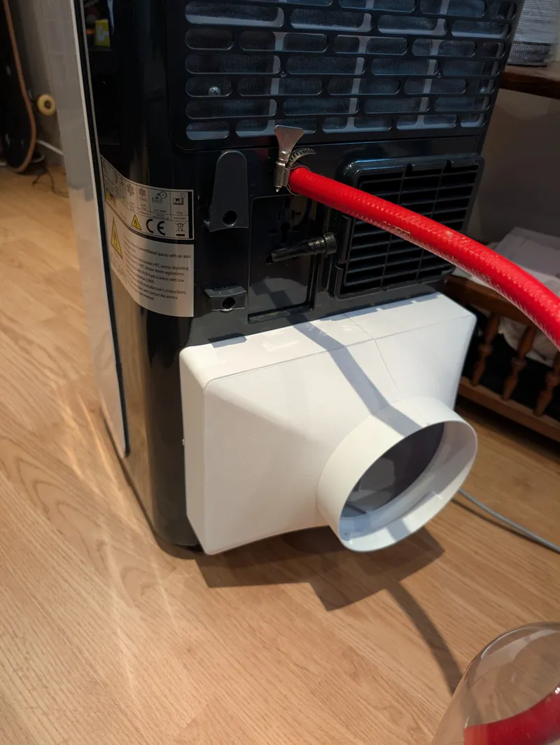 Een wit PETG koppelstuk om de airco te kunnen voeden met buitenlucht i.p.v. binnenlucht