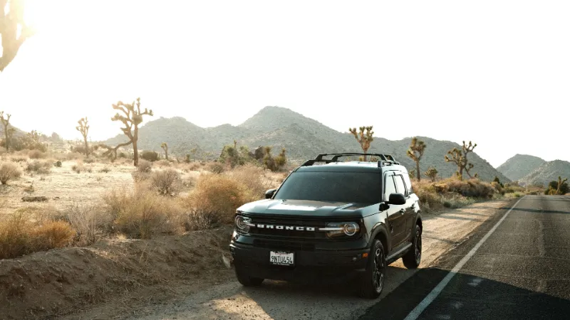 Un SUV compacto estacionado en una ruta entre joshua trees, en California