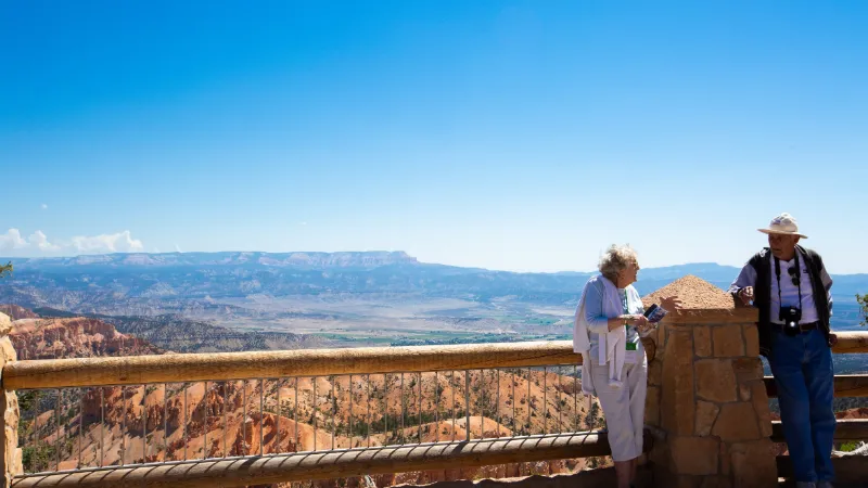 Dos personas mayores apoyadas en la baranda de un mirador de un parque nacional