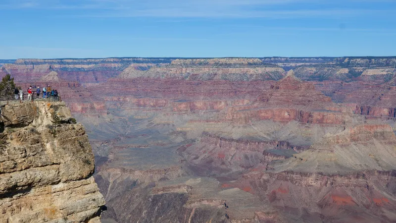 Mirador del South Rim del Gran Cañón con visitantes asomados al borde