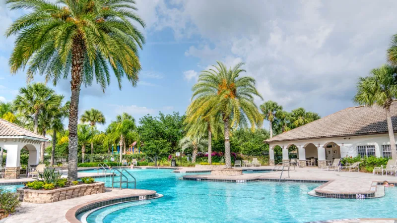 Piscina con palmeras en un complejo de casas vacacionales
