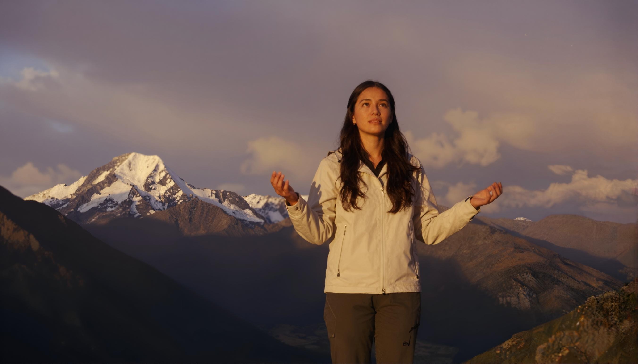 Woman standing before a breathtaking mountain landscape — AI image generation