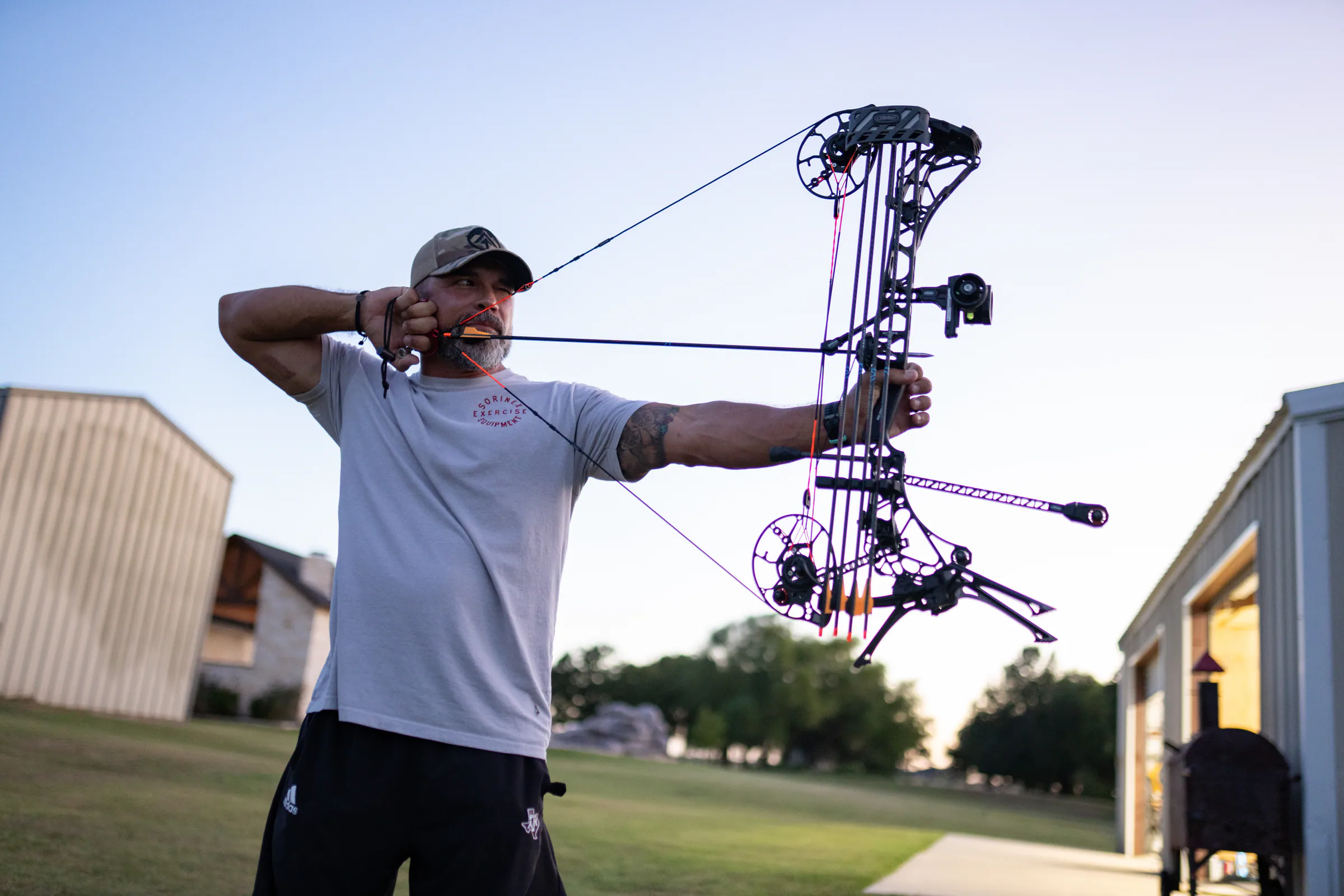 Athlete drawing a compound bow on an outdoor range