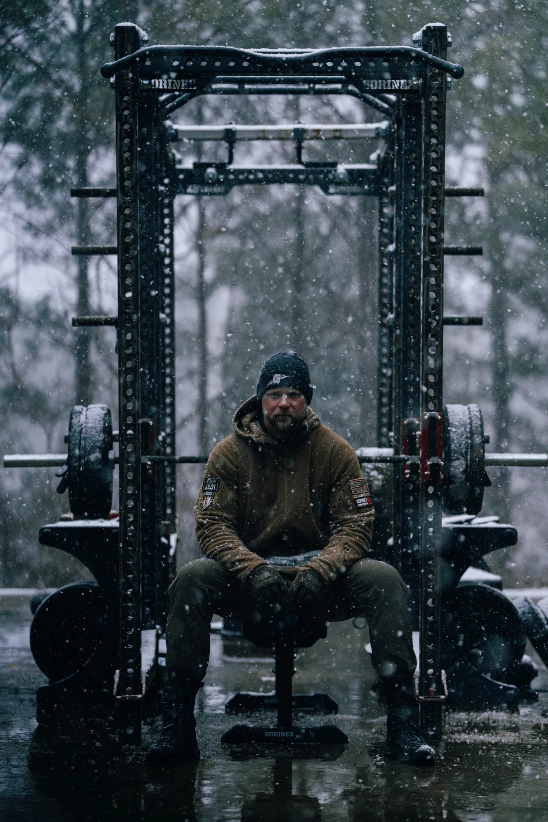 Athlete resting inside an outdoor squat rack in deep snow