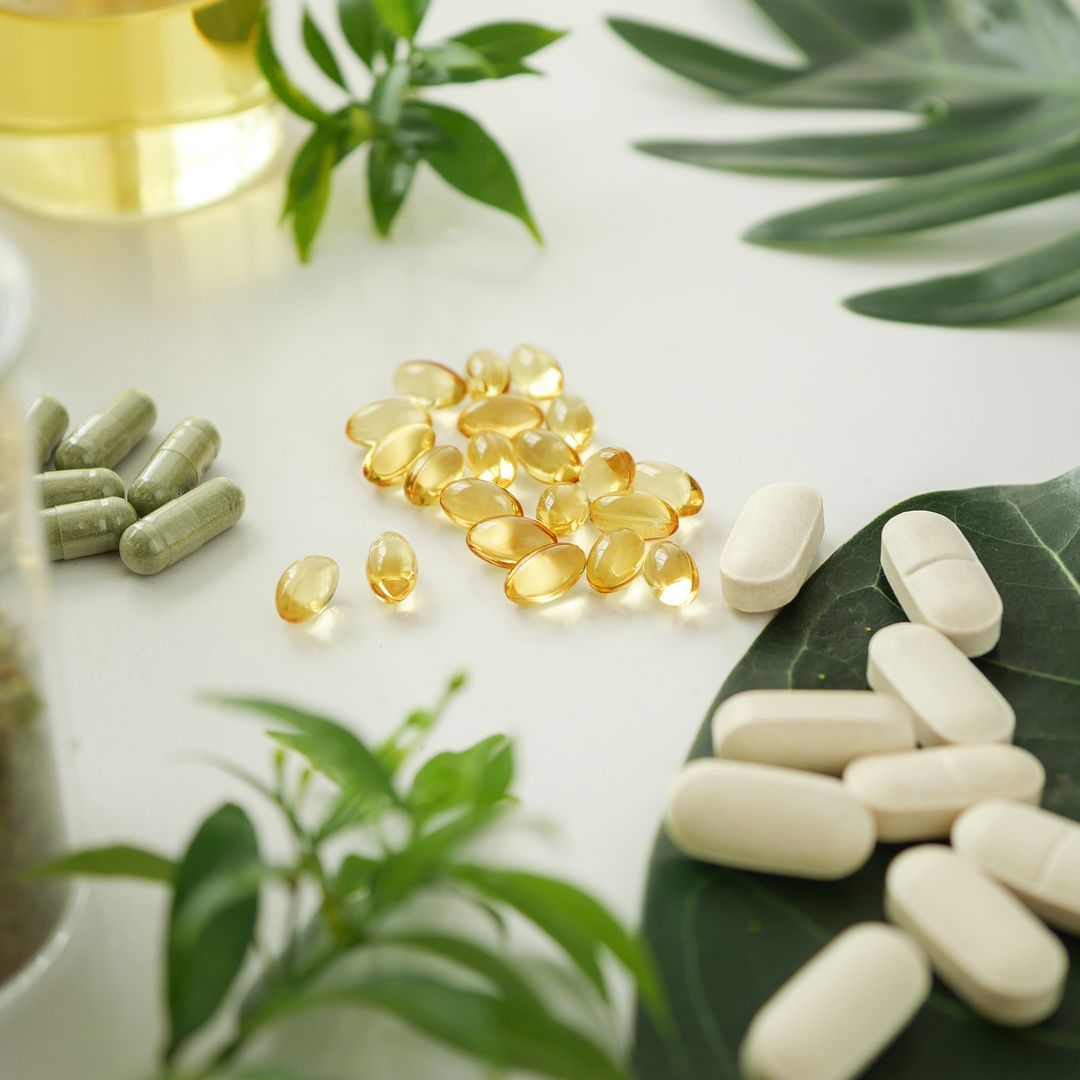 Small groups of various supplements arranged on a white table and with some leaves