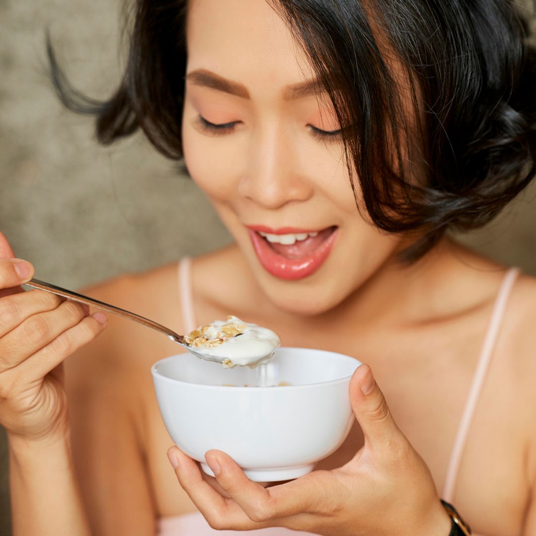 Woman holding a small bowl of natural yoghurt.