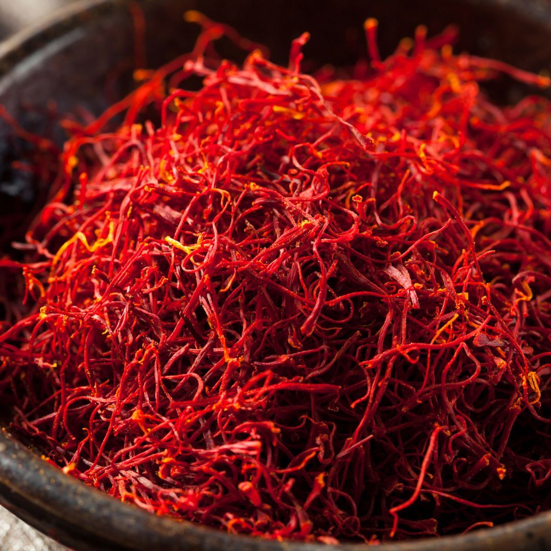 Brown bowl filled with raw organic red saffron.