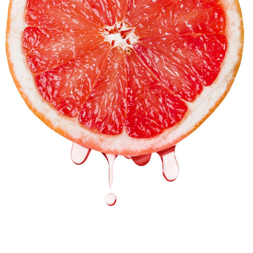 A slice of ripe grapefruit with drops of juice isolated on a white background.
