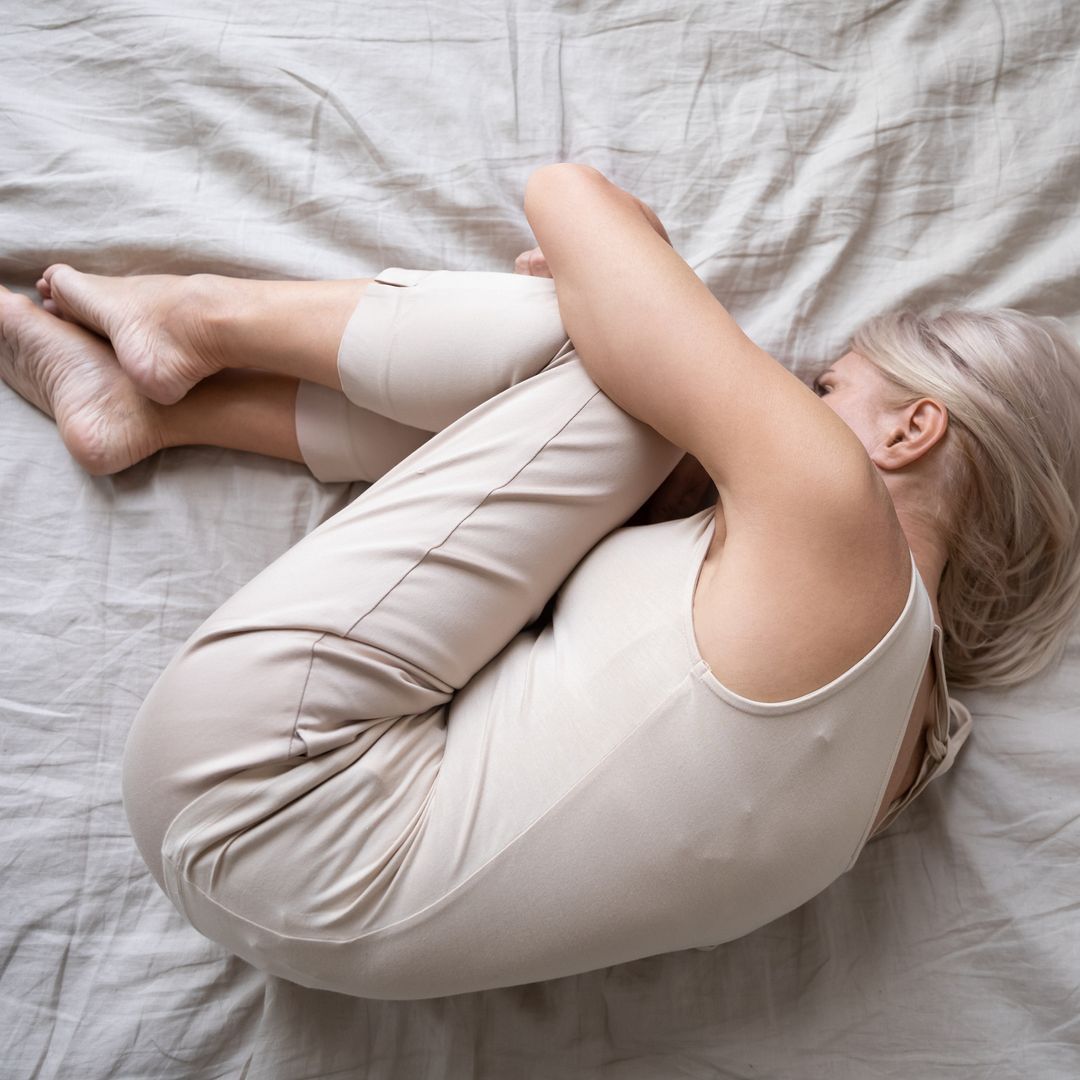 Woman in foetal position lying in bed