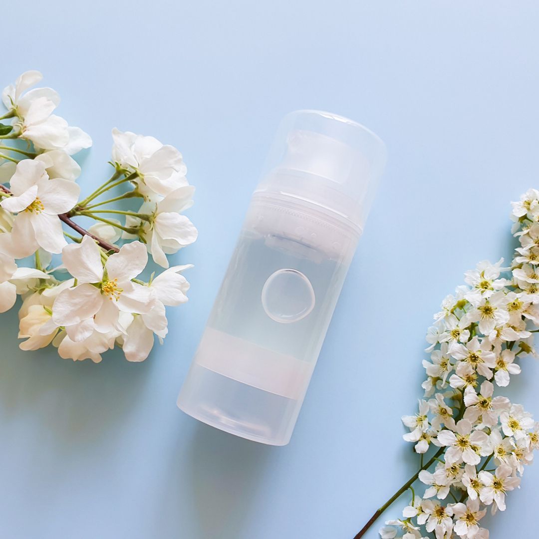 Transparent bottle of intimate lubricant gel on a blue background with white flowers.