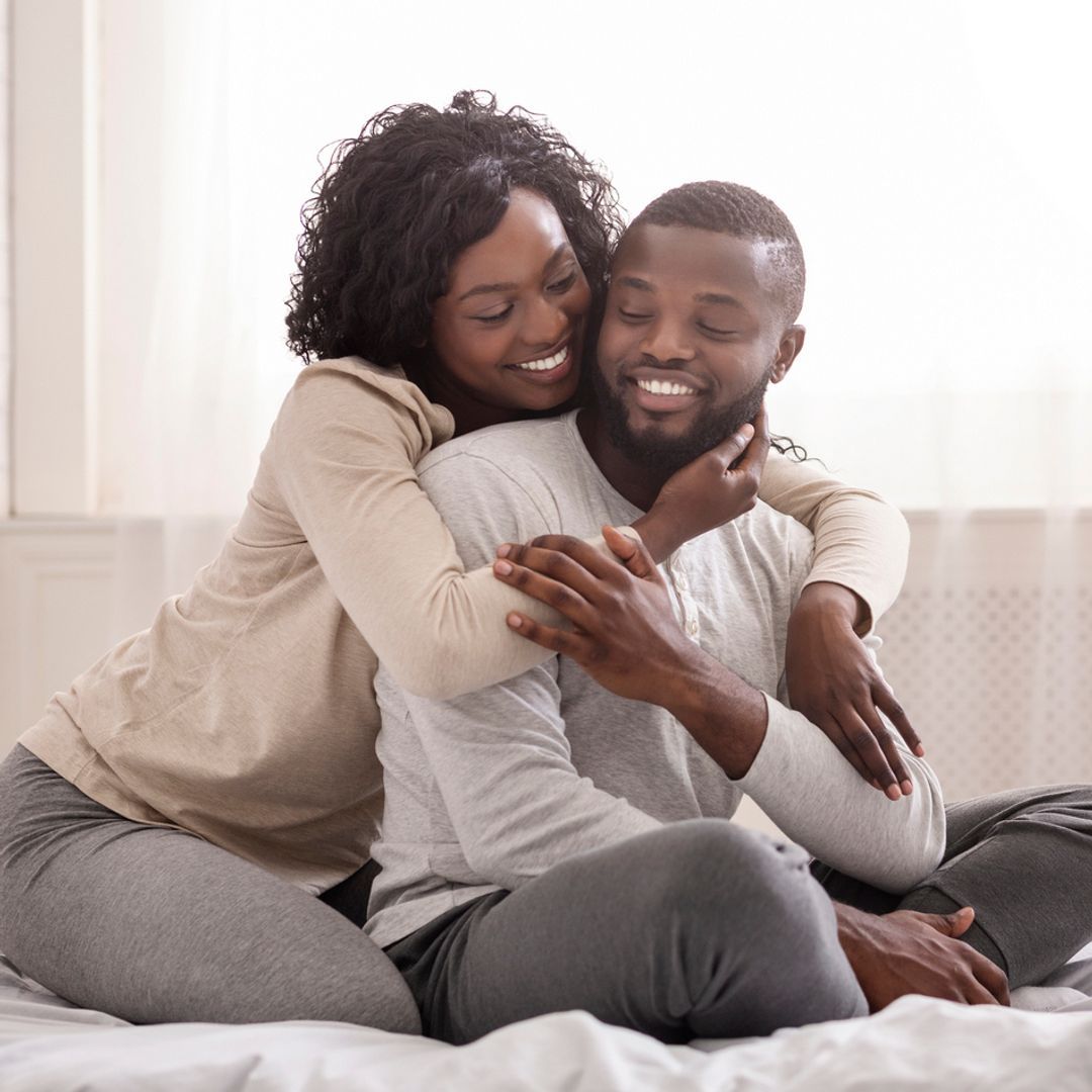 Happy couple cuddling on the bed at home and bonding with each other.