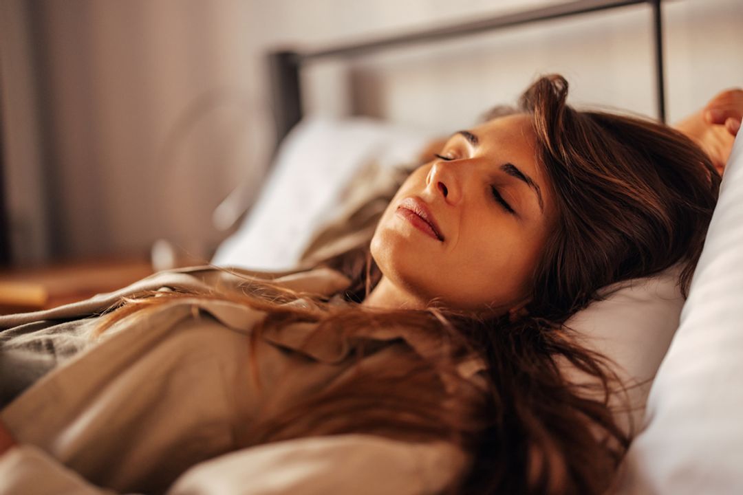  A woman sleeping peacefully in a bed with a soft light.