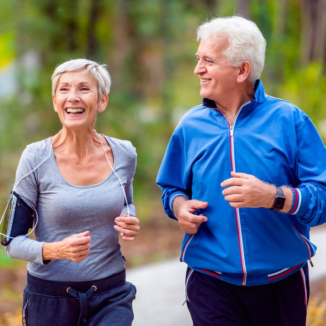 Older couple smiling and running in the park.