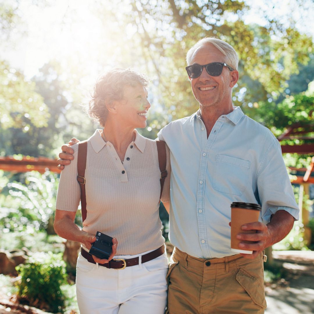  Senior couple walking around a park in the sun.