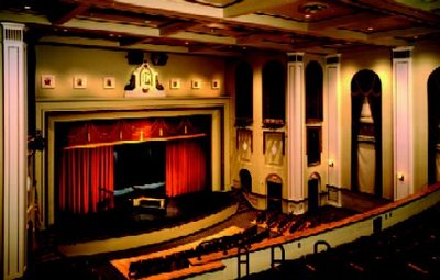Color view from the auditorium balcony toward the stage, grand piano, golden proscenium and tall windows