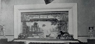 Historic auditorium stage with a painted landscape backdrop, chairs and grand piano