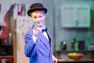 Tiger Drama performer in a blue suit and bowler hat pointing toward the audience