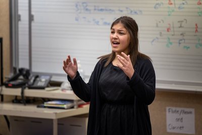 Tiger Drama student performing with hands raised in a music classroom