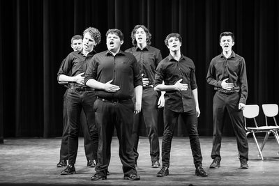 Black-and-white photograph of six Tiger Drama performers singing onstage in Dogfight