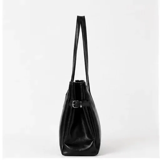 Side view of the black Big Nicole bag, showing its depth, long handles, and side buckle.