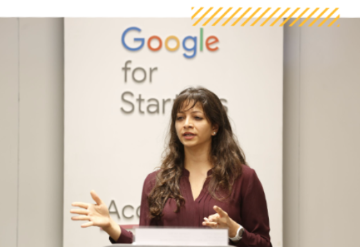 Indian woman speaking at a podium with the Google for Startups logo in the background.