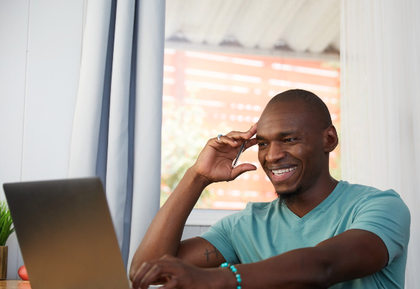 Мужчина с улыбкой смотрит на свой ноутбук во время обучения Google