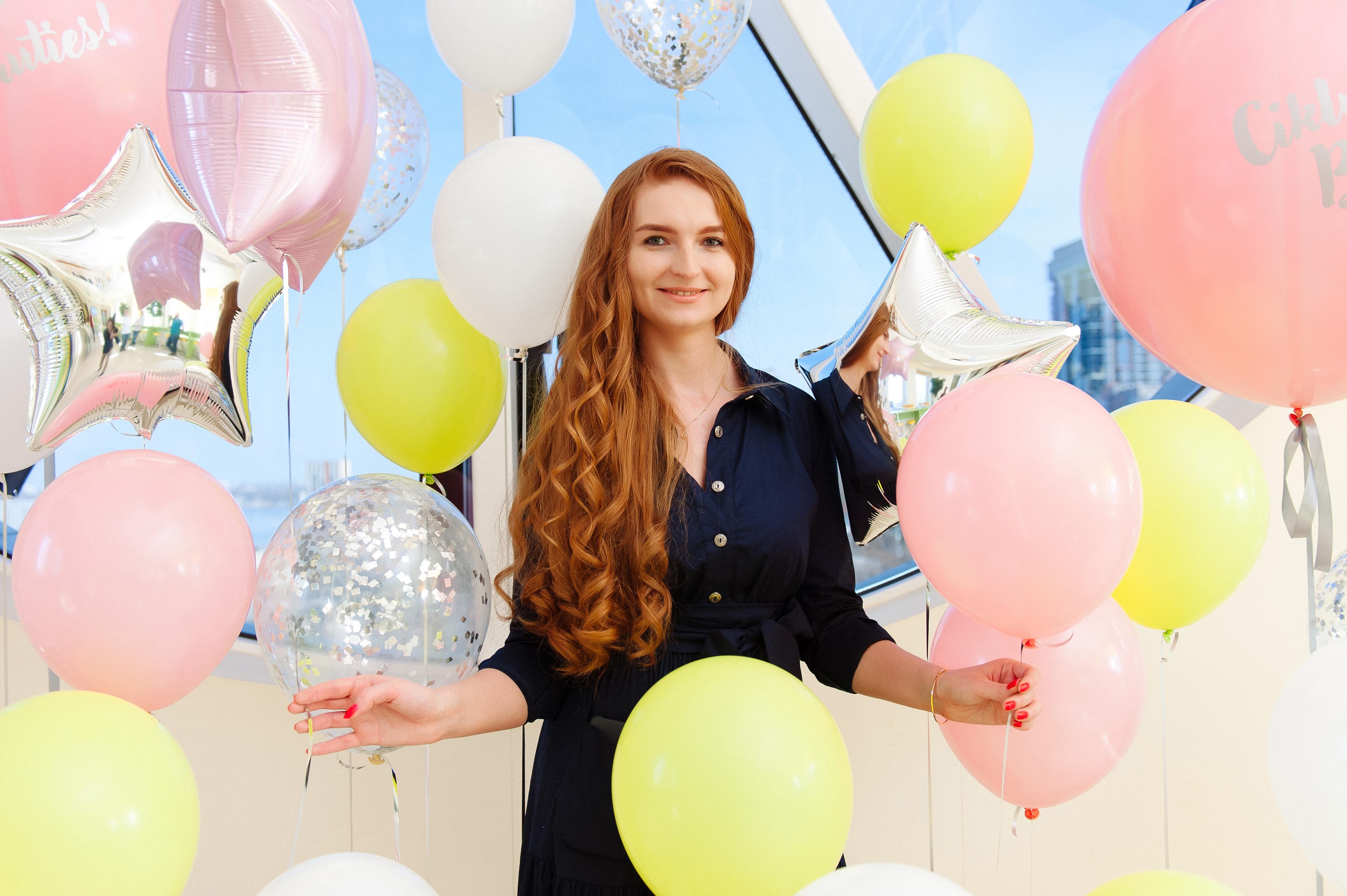 A photo of Anna, a caucasian woman with red hair and a black shirt, smiling at the camera.