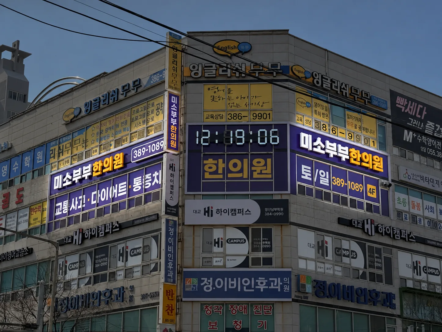 측면에서 본 코너 간판, 좌측면과 정면 간판, 세로형 돌출 간판이 함께 보인다