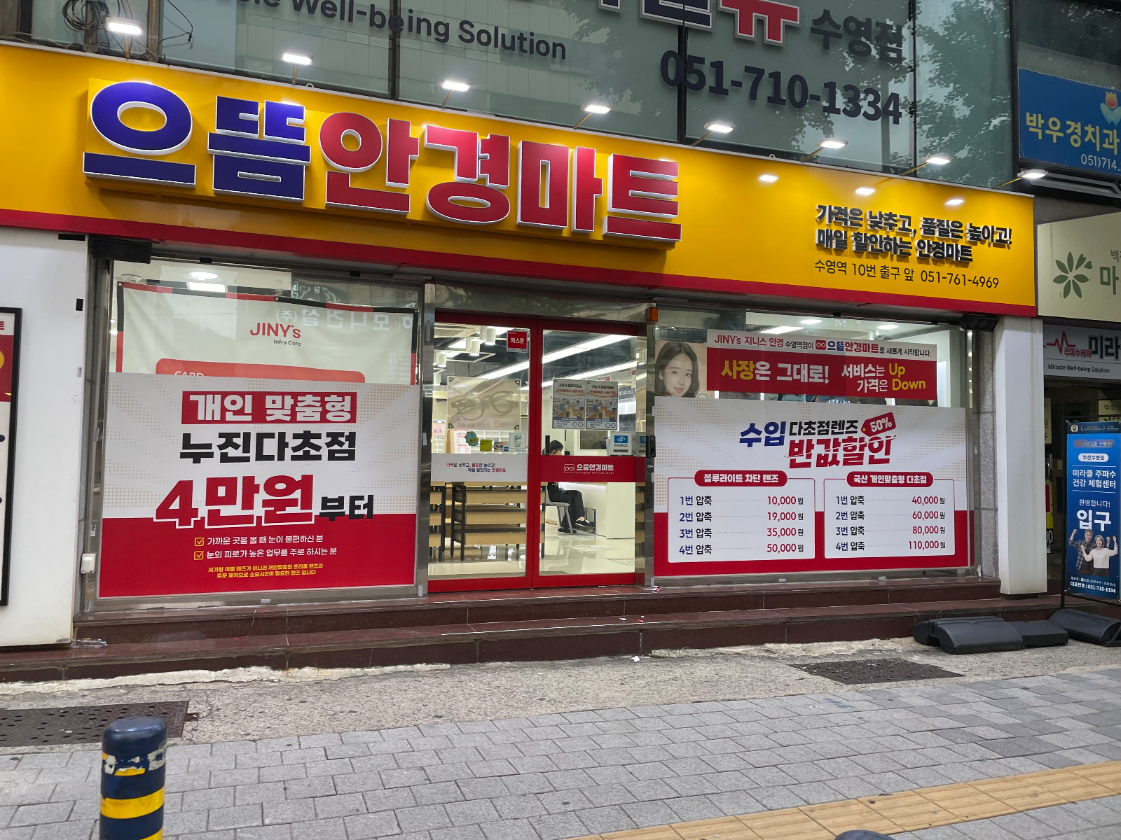 정면에서 본 노란 간판과 렌즈 가격 안내가 붙은 유리창
