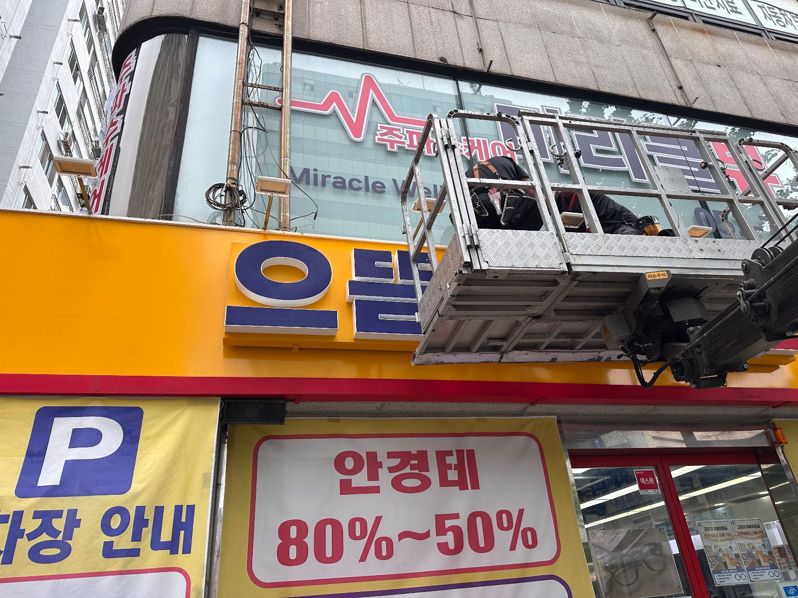 고소작업차 바스켓에서 간판 글자 위치를 맞추는 작업자