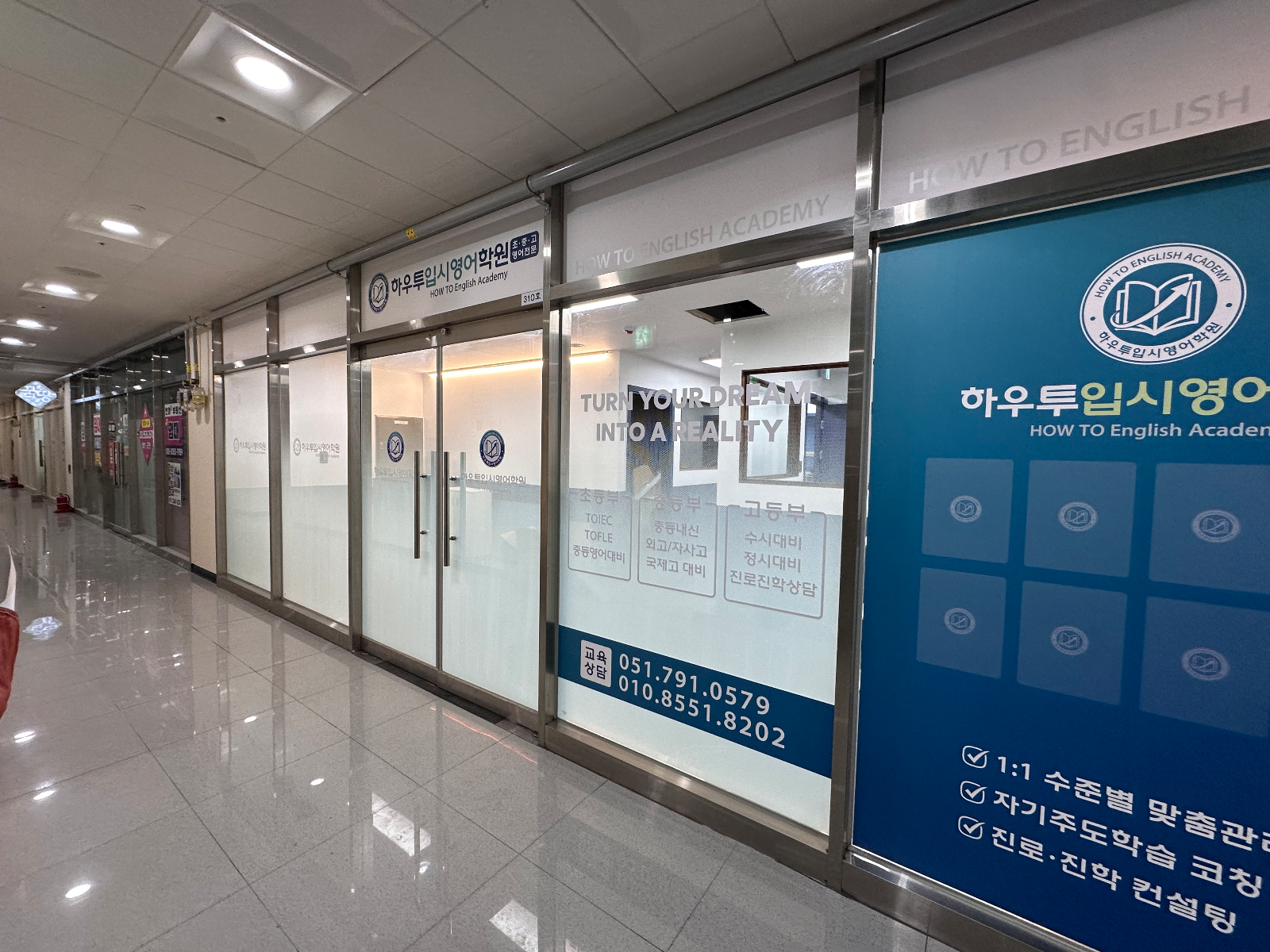 긴 복도 끝에서 본 학원 유리창과 주변 상가